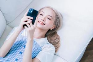 ung asiatisk tjej använder smartphone hemma foto