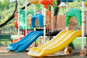 lekplats för barn som har kul med färgglada rutschkanor på trädgårdsaktiviteter i offentlig park. foto