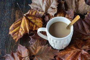 vit tröja mönstrad kaffekopp mugg kaffe omgiven av höstlöv foto