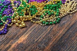 mardi gras lila, gröna och guldpärlor på träbord med kopia utrymme foto