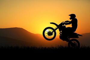 siluett av en motocrossmotorcykel som lyfter framhjulet. äventyrs- och actionkoncept foto