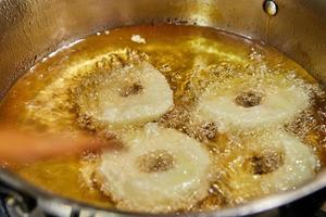laga äppelpannkaka. kocken vänder äppelmunken i den sjudande oljan foto