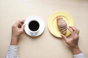 kaffe och croissant på träbord, ovanifrån. foto