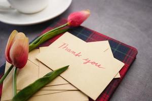 tack meddelande, kuvert tulpan blomma på bordet foto