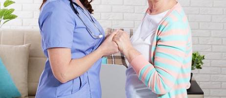 närbild av läkarens hand på den av funktionshindrade kvinna närbild, sjuksköterska och äldre kvinna foto