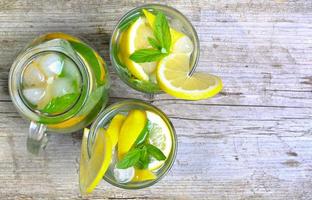 citronsaft. vatten med citron och mynta i ett glas foto