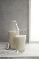 mjölkflaska och fullt glas mjölk i fönsterbrädan foto