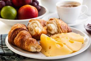 croissanter med ost, frukt och kaffe foto