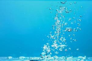 abstrakt bakgrundsbild av bubblor i vatten. rent vatten med vattendroppar och vågor. färskvatten ett glas med bubblor blå bakgrund. foto