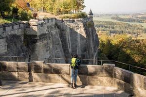 youmg kvinna med ryggsäck står på det gamla tyska slottet i sachsiska schweiz nationalpark foto