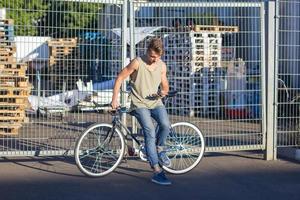 ung, man promenad med fixie cykel, urban bakgrund, bild av hipster med cykel i blå färger foto