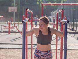 ung stark kvinna tränar utomhus på sommaren, kvinnlig professionell idrottare gör övningar i parken foto