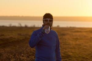 ung man trail runner utbildning utomhus på fälten, solnedgång i sjön bakgrund foto