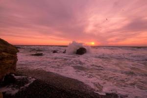 vackert havslandskap i soluppgångstid, färgglad rosa och orange himmel och storm i havet. foto