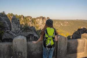 youmg kvinna med ryggsäck står på det gamla tyska slottet i sachsiska schweiz nationalpark foto