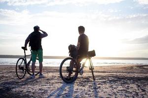 två unga män på en turcykel med ryggsäckar och hjälmar i öknen på en cykeltur foto