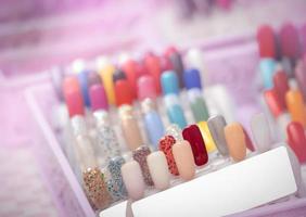 färgglada konstgjorda naglar i nagelsalongsbutik. uppsättning lösnaglar för kunden att välja färg för manikyr eller pedikyr i nagelsalong och spabutik. nagelkonst och design. prov på nagellackspalett. foto