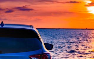 blå kompakt suv-bil med sport och modern design parkerad på betongväg vid havet i solnedgången. miljövänlig teknik. elbilsteknik och affärer. hybridbilar och bilar. foto