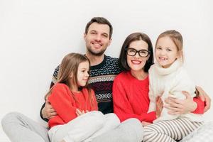 inomhus bild av lycklig familj njuta av samvaro, fritid under helgen hemma, posera för tidningen. glad orakad man, hans man och två små döttrar isolerad på vit studiobakgrund foto