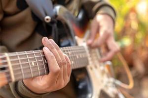 kvinnlig hand spelar utomhus elektrisk gitarr. foto