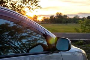 soluppgången tidigt på morgonen, reflekterar spegeln utanför bilen. foto