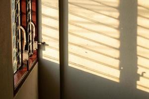solljus skugga på väggen med gamla lamellfönster. foto