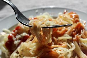 spaghetti med ketchup och ost på en tallrik foto
