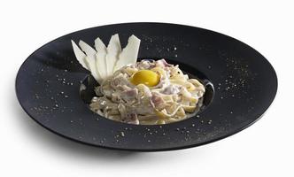 pasta carbonara dekorerad med skivor av parmesan och äggula