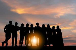 siluett av affärsmän firande framgång lycka team står med armarna i kors vid solnedgången kväll himmel bakgrund foto