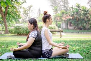 unga kvinnor och vän gör yoga i parken, hälsosam och livsstilskoncept foto