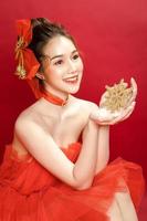 ung asiatisk vacker kvinna modell i en posh elegant lyxig röd klänning på en röd bakgrund isolerad. foto