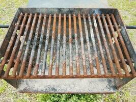 brunrostade metallstänger på grillen med sot och ett hål foto