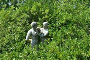 Adam och Eva staty med äpple och gröna växter foto
