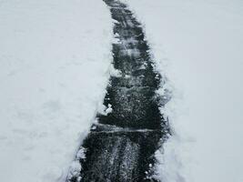 asfalt uppfart med vit snö skottning på vintern foto