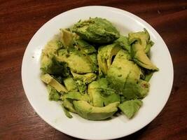 skål med grön avokado eller guacamole på brunt träbord foto
