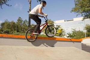 bmx ryttare tränar och gör tricks i street plaza, cykel stunt ryttare i cocncrete skatepark foto