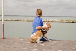 ung kvinna i blå klänning har goot tid med beagle hund foto