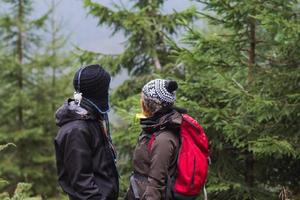 ungt par vandrare med termoskoppar i skogen, resenärer på berg som dricker te eller kaffe foto