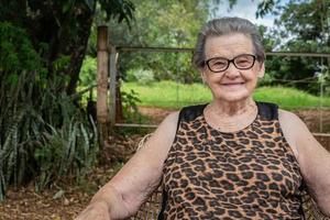 senior glad gammal bondekvinna med glasögon som ler och tittar på kameran foto