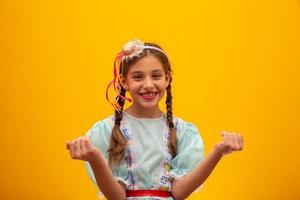 barn i typiska kläder från den berömda brasilianska festen som kallas festa junina för att fira sao joao. vacker flicka på gul bakgrund. foto