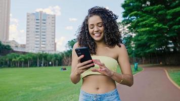 latinsk kvinna med smartphone i parken. Brasiliansk tjej. foto