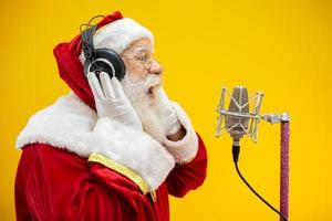 jultomten sjunger eller talar i en studiomikrofon. god Jul. sändare. utropare. befordran. julmusik koncept. foto
