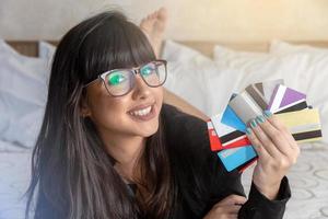 vacker kvinna som håller en hand flera kreditkort på sängen. plastpengar, elektroniska pengar och digitala pengar kommer att förändra den globala marknadsföringen inom en snar framtid. begreppet rik kvinna. foto