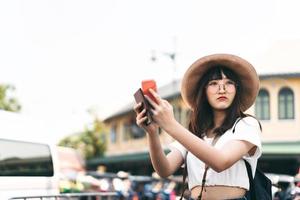 asiatisk student college glasögon kvinna resenär förlorade i resa och använda smart telefon för att hitta karta. foto