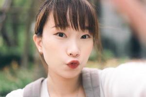 porträtt av ung söt asiatisk tonåring student kvinna ta en selfie foto med mobiltelefon