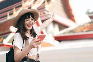 asiatiska energiska glasögon flicka modern stil lyssna på strömmande musik med smart telefon. foto