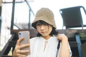 selfie ung vuxen asiatisk kvinna som använder mobiltelefon för sociala medieapplikationer. foto