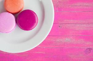 macarons i tallrik på vintage rosa färg trä bakgrund foto