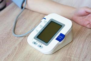 kvinna som använder digital blodtrycksmätare foto