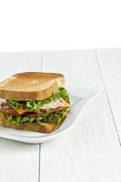 skinkasmörgås med rostat bröd på den vita plattan foto